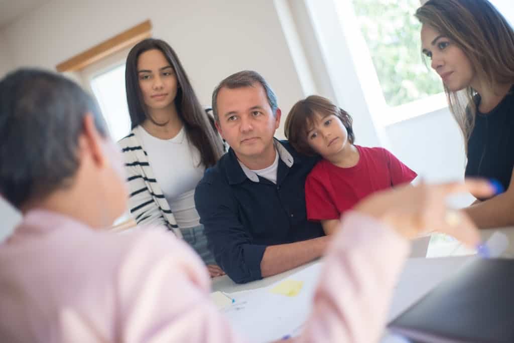 A family of four seeks advice from a professional during an indoor consultation in a bright room.