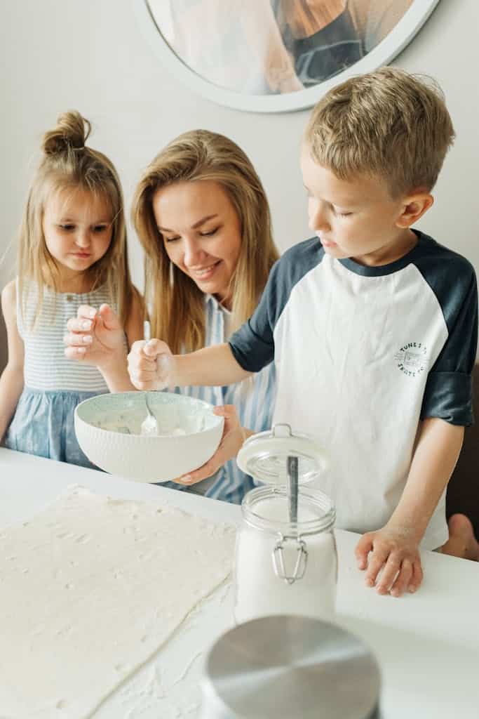 A joyful family moment in the kitchen as a mother and her children mix ingredients.