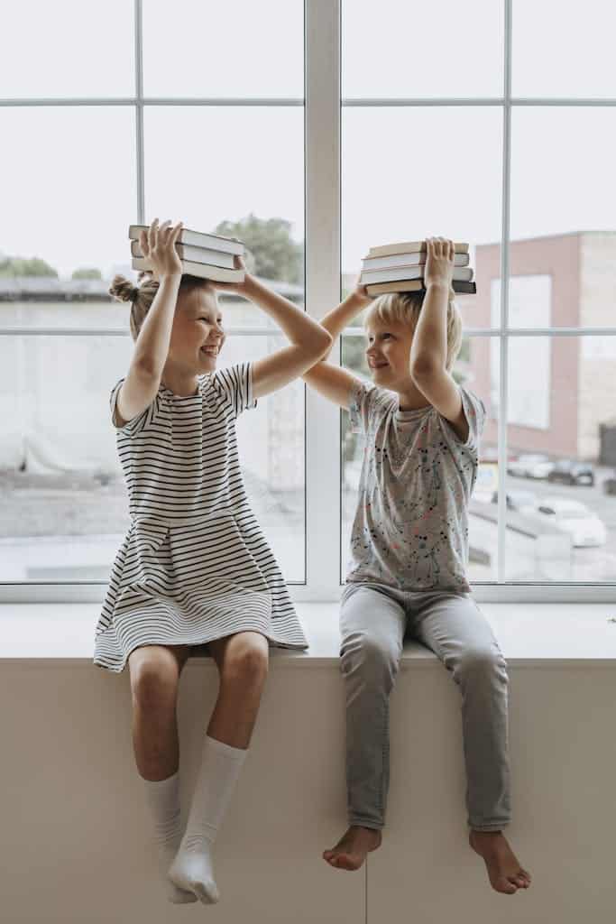 Two happy children playing with books, embodying the joy of learning together.